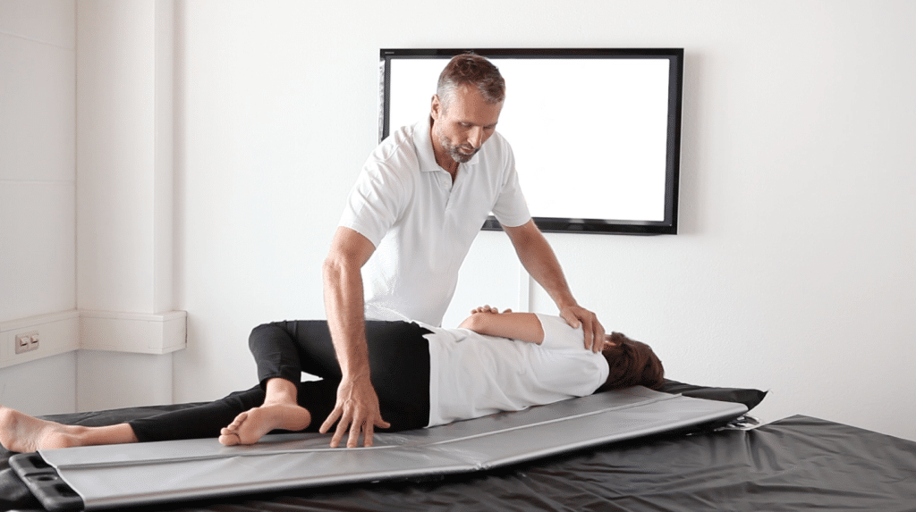 Man using a Rollboard transfer device to transfer a patient from a stretcher to a bed