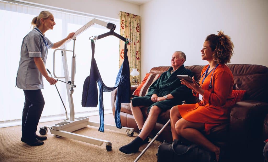 Care worker using a hoist in a patient's own home