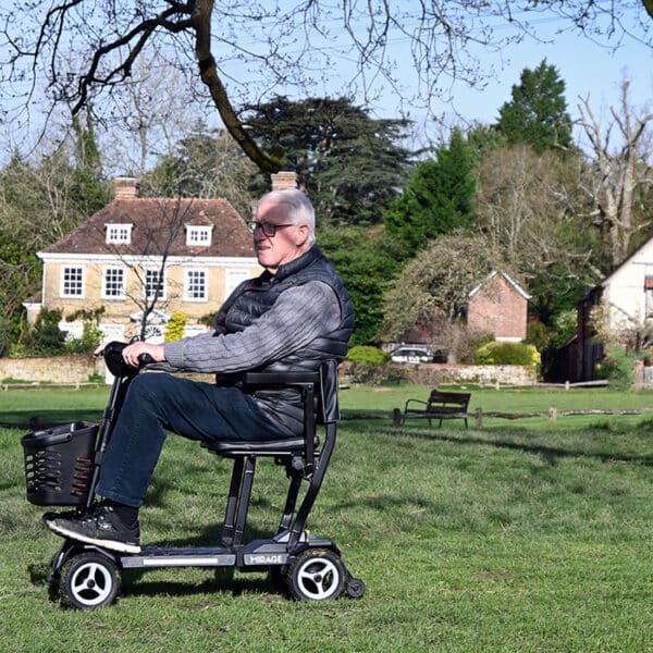 Man driving Mirage folding mobility scooter on grass