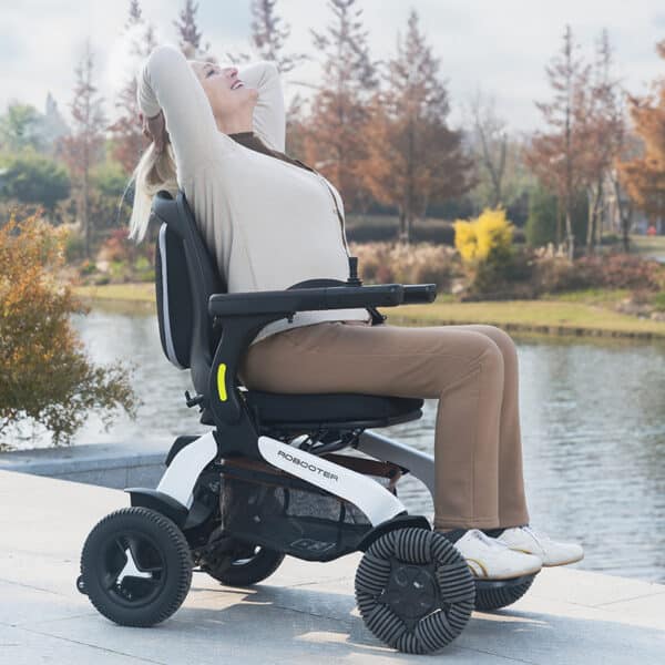 Lady relaxing by a river on the Robooter E60 electric wheelchair