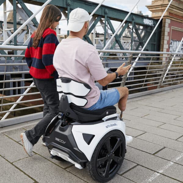 Man on Genny Zero Powerchair with lady walking beside